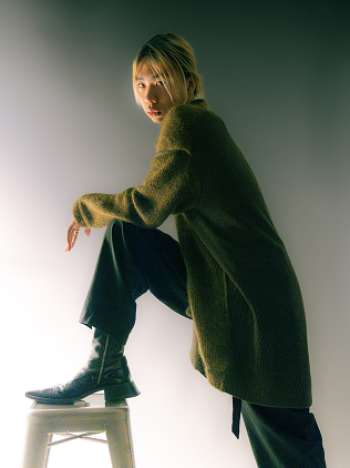 A confident model wearing a knit sweater and black pants.