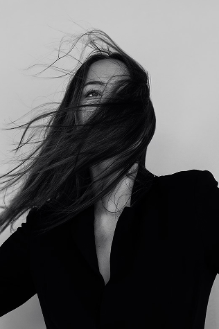 A dynamic portrait showcasing hair movement of a woman in black attire.