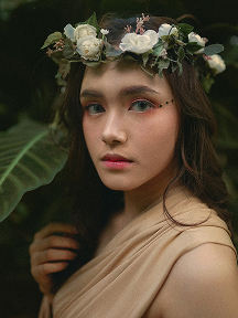 A serene portrait of a woman with delicate makeup and a floral headpiece.