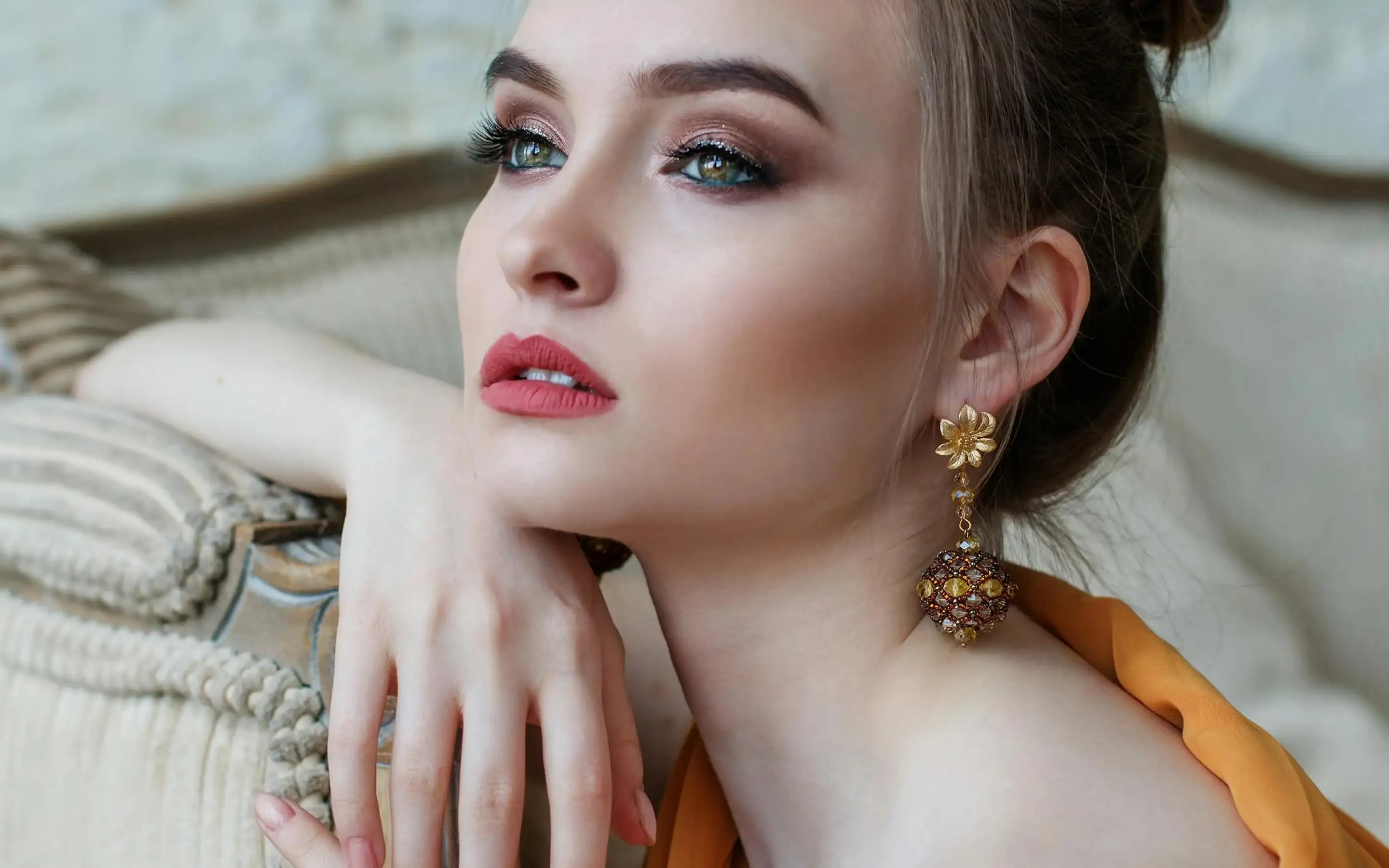 Portrait of a woman with glamorous makeup and statement earrings.