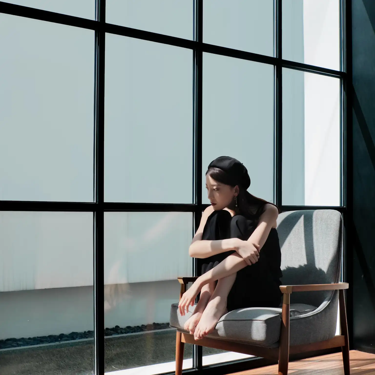 A woman relaxing in a modern space, sitting comfortably in a chair by the window.