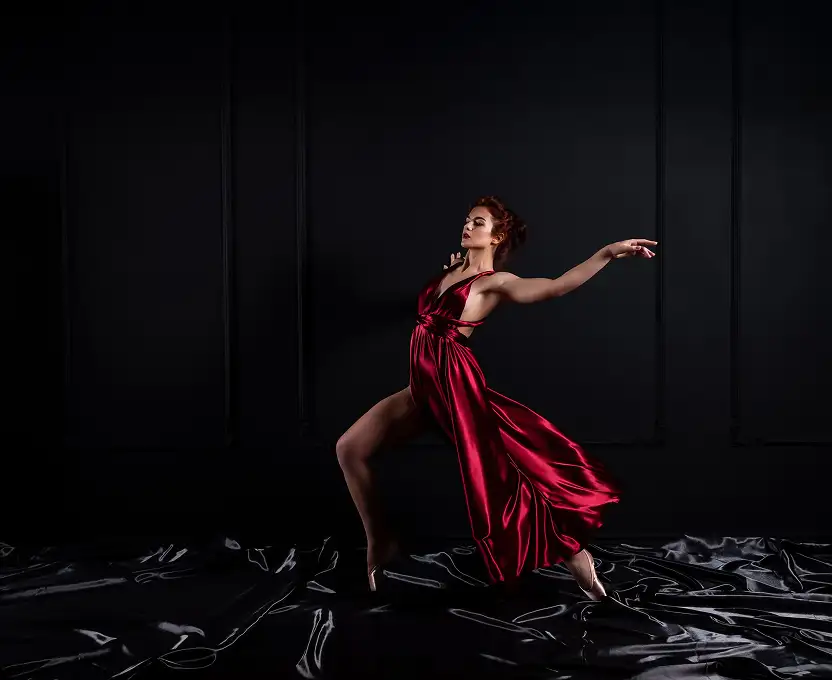 A dancer in a flowing red dress performing gracefully against a dark backdrop.